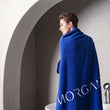 Load image into Gallery viewer, A woman wearing a blue Morgan & Tina luxurious Egyptian cotton bath towel in front of a bathtub.