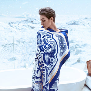 A white woman with blonde hair and blue eyes wrapped in Morgan & Tina's blue artistic quick dry bath towel.